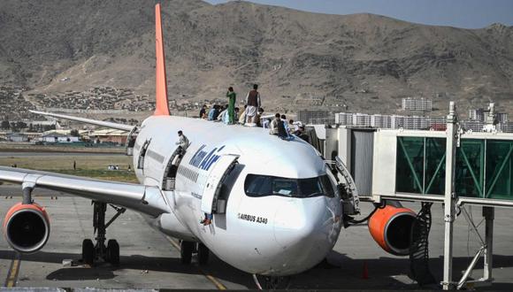 Los afganos se suben a un avión mientras esperan en el aeropuerto de Kabul después de un final asombrosamente rápido de la guerra de 20 años de Afganistán, mientras miles de personas asaltaron el aeropuerto de la ciudad tratando de huir de la temida marca de línea dura del grupo. (Foto: Wakil Kohsar / AFP).
