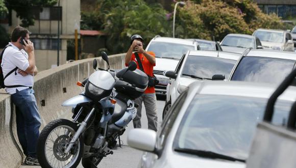 Los automovilistas se detienen en la carretera cerca de una torre de telefonía celular en funcionamiento durante los apagones en Caracas, Venezuela. (Foto: AP)