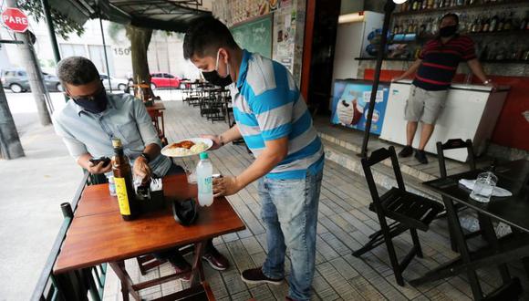 Un camarero atiende a un cliente en un bar después de la reapertura de gimnasios, restaurantes e instalaciones deportivas en las playas a medida que la ciudad alivia las restricciones, en medio del brote de la enfermedad del coronavirus (COVID-19) en Río de Janeiro. (Foto: REUTERS / Sergio Moraes).