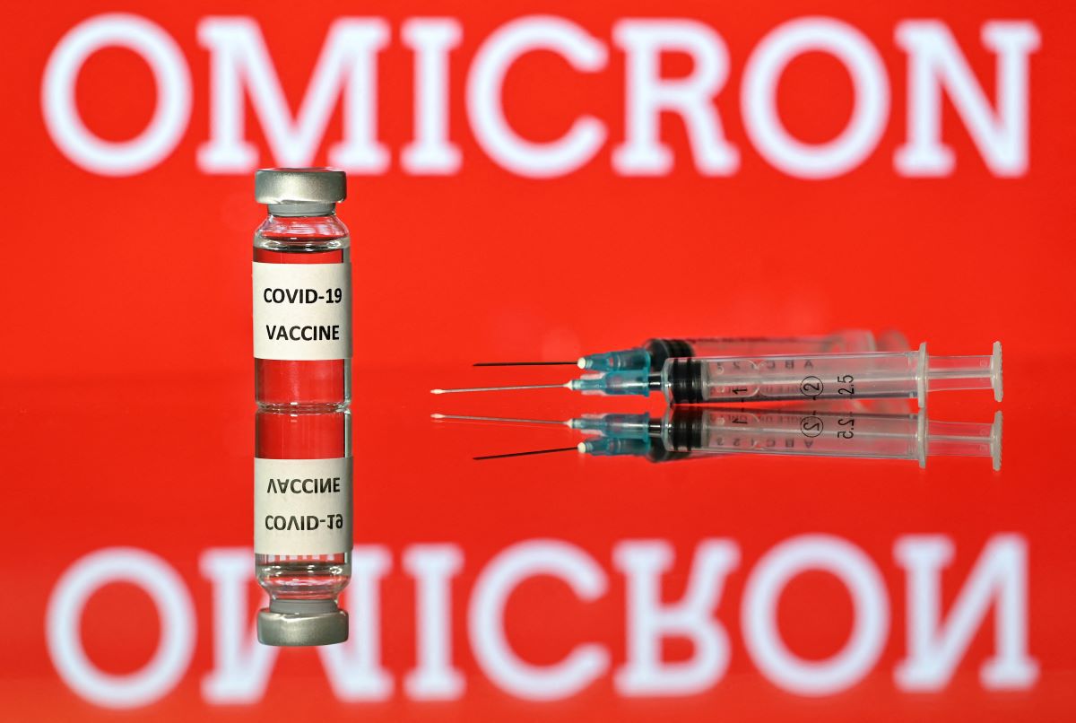 An illustration image taken in London on December 2, 2021 shows a vial with the Covid-19 vaccine label attached, along with syringes and a screen showing the word omicron, the name of the new variant of the coronavirus.  (Justin TALLIS / AFP).