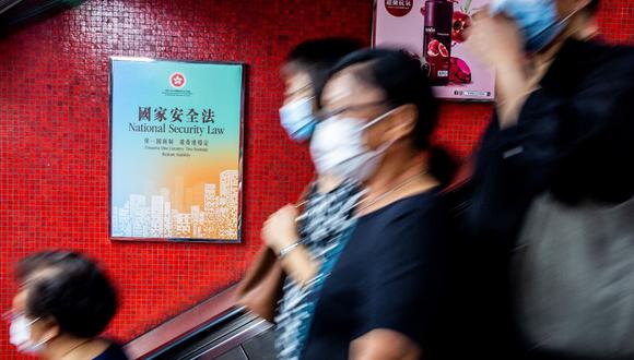 Un anuncio del gobierno (a la izquierda) que promueve la ley de seguridad nacional planificada por China se muestra dentro de una estación de trenes MTR en Hong Kong. (ISAAC LAWRENCE / AFP)