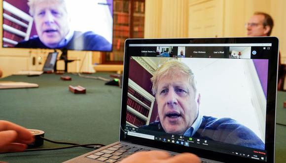 Esta foto del 28 de marzo del 2020, muestra una imagen del primer ministro británico, Boris Johnson, en una pantalla de computadora mientras preside de forma remota una reunión sobre el coronavirus. Johnson está confinado desde que diera positivo el 27 de marzo de COVID-19, tras presentar síntomas leves. (Foto: AFP)