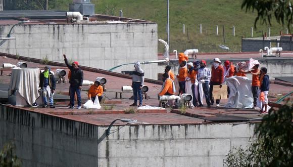 Los reclusos se ven en el techo de la prisión CRS Turi después de un motín en Cuenca, Ecuador, el 3 de abril de 2022. (Foto de FERNANDO MACHADO / AFP)