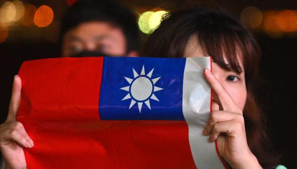 Una mujer sostiene una bandera taiwanesa mientras se une a otros en una manifestación para conmemorar el Día Nacional de Taiwán, en el distrito de Tsim Sha Tsui en Hong Kong el 10 de octubre de 2019. (PHILIP FONG / AFP).