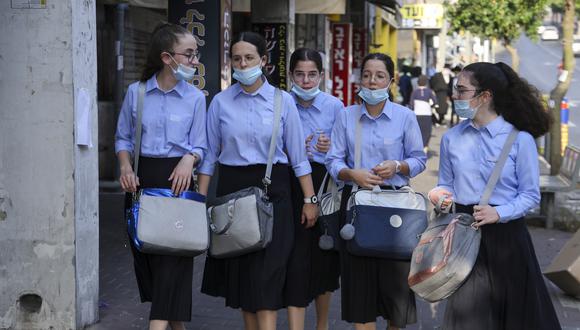 Colegialas judías ultraortodoxas, con máscaras protectoras debido a la pandemia del coronavirus COVID-19, caminan por una calle en la ciudad de Bnei Brak, cerca de Tel Aviv, Israel. (Foto de MENAHEM KAHANA / AFP).