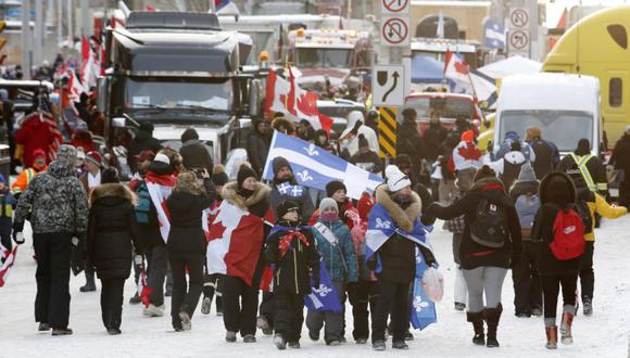 La gente camina frente a los camiones que bloquean una calle del centro durante una protesta contra las medidas de COVID-19 que se ha convertido en una protesta antigubernamental más amplia en Ottawa, Ontario. (Foto: Patrick Doyle/The Canadian Press vía AP )