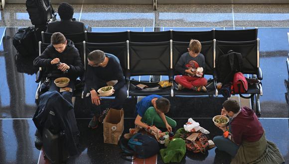 Una familia disfruta de una comida mientras esperan un vuelo en el Aeropuerto Nacional Reagan durante una tormenta de invierno antes de las vacaciones de Navidad, en Arlington, Virginia.