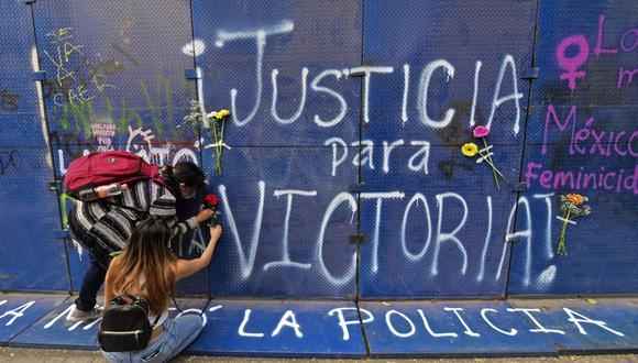 Manifestantes colocan flores junto a un graffiti que dice "Justicia para Victoria"' durante una protesta en la Ciudad de México. (Foto de PEDRO PARDO / AFP).