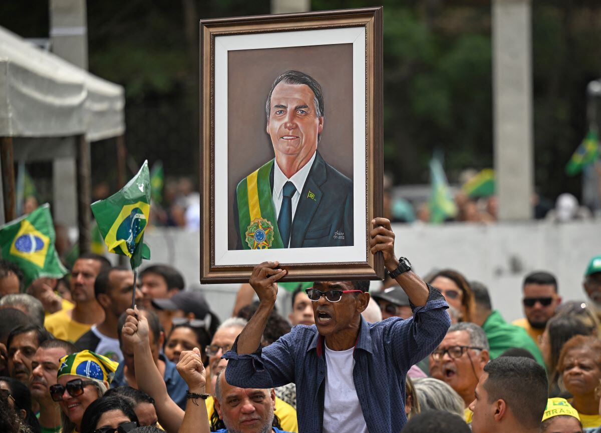 A supporter displays a painting depicting Brazil's president and re-election candidate Jair Bolsonaro during a campaign rally in Sao Goncalo, Rio de Janeiro, on October 18, 2022. (CARL DE SOUZA / AFP)