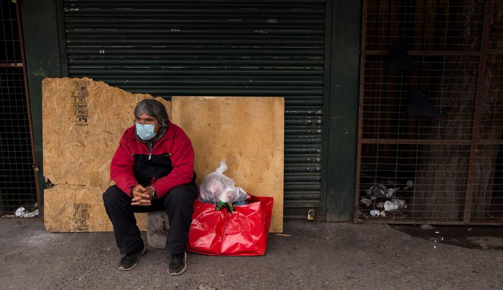 Roberto, un habitante de calle, descansa junto a la entrada del servicio de urgencias del Hospital San José, uno de los principales centros médicos en enfrentar la pandemia del coronavirus en Santiago. (EFE/Alberto Valdés).