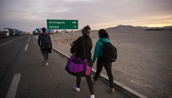 Migrantes venezolanos caminan por la carretera camino a Iquique, luego de cruzar desde Bolivia a Chile, el 18 de febrero de 2021. (Foto por Martín BERNETTI / AFP).