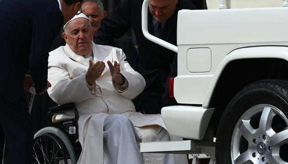 El papa Francisco habla con sus ayudantes antes de que lo suban a su papamóvil desde su silla de ruedas, el 29 de marzo de 2023 tras la audiencia general semanal en la plaza de San Pedro. (Foto de Vincenzo PINTO / AFP).