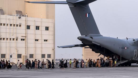 Evacuados de Afganistán caminan sobre la pista mientras desembarcan de un avión de transporte militar Airbus A400M en la base aérea militar francesa 104 de Al Dhafra, cerca de Abu Dhabi. (BERTRAND GUAY / AFP).