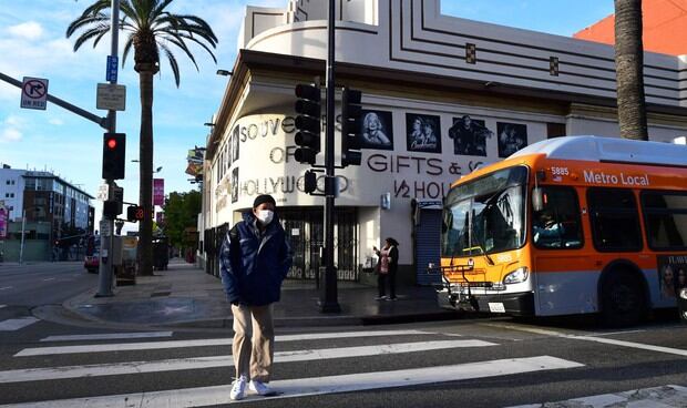 Un hombre usa una máscara facial mientras cruza una calle en Hollywood, California, un día después de que el condado de Los Ángeles anunciara un cierre casi total, instando a todos los residentes a quedarse en casa, excepto por las necesidades esenciales debido a la pandemia de coronavirus (Foto: AFP)