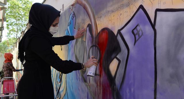 La artista Shamsia Hassani es la primera mujer grafitera de Afganistán. La foto es del año 2013, cuando se intervinieron las paredes del Centro Cultural Francés en Kabul (Foto: AFP)