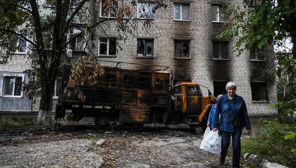 Dos mujeres pasan frente a una residencia destruida en Balakliya, región de Kharkiv, el 17 de septiembre de 2022, en medio de la invasión rusa de Ucrania. (Foto por Juan BARRETO / AFP)
