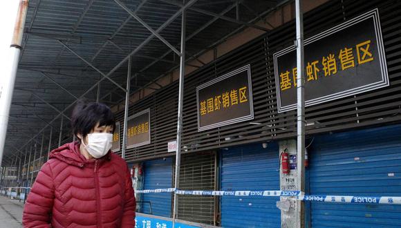 Esta foto de archivo tomada el 12 de enero de 2020 muestra a una mujer caminando frente al cerrado mercado mayorista de mariscos de Wuhan, donde se cree que se dio el primer caso de coronavirus covid-19. (Foto de Noel Celis / AFP).