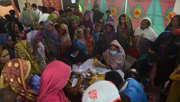 Los residentes locales desplazados por las inundaciones se reúnen en un campamento médico improvisado ubicado en el distrito de Dadu, provincia de Sindh, el 27 de septiembre de 2022. (Foto de Rizwan TABASSUM / AFP)