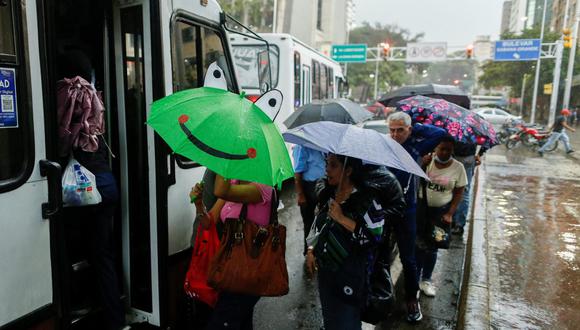 Ciudadanos se resguardan de las lluvias causadas por el ciclón tropical Dos antes de abordar un bus en Caracas, capital de Venezuela.