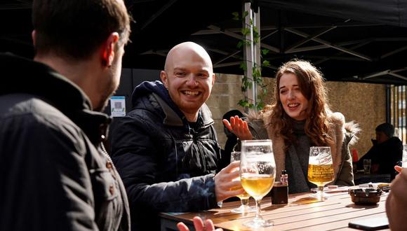 Los clientes se sientan en una mesa al aire libre mientras disfrutan de la comida y las bebidas en el pub Half Moon en el este de Londres, Inglaterra, mientras se alivian las restricciones dictadas por el coronavirus. (Foto de Niklas HALLE'N / AFP).
