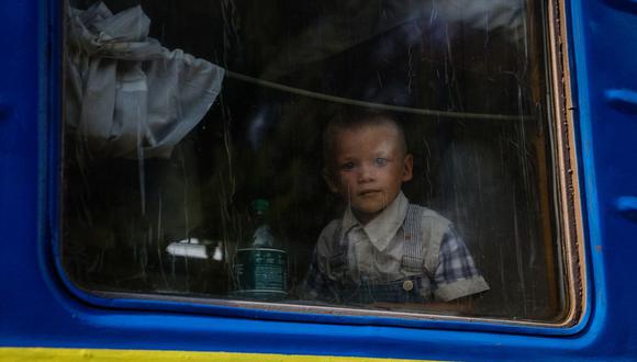 Un niño mira por la ventana de un tren de evacuación de la región de Donbas al oeste de Ucrania, en la estación de tren de Udachnoye, el 16 de agosto de 2022, en medio de la invasión rusa de Ucrania. (Foto de ANATOLII STEPANOV / AFP)