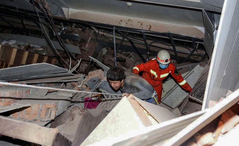 Los rescatistas ayudan a un hombre que estaba atrapado entre los escombros de un hotel derrumbado en Quanzhou, en la provincia oriental china de Fujian. En este lugar había personas en cuarentena por el coronavirus. (AFP).