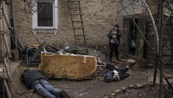 Ira Gavriluk carga a su gato mientras pasa cerca de los cadáveres de su esposo, su hermano y otro hombre, los cuales fueron asesinados en el exterior de su casa en Bucha, en las afueras de Kiev, Ucrania. (Foto AP/Felipe Dana).