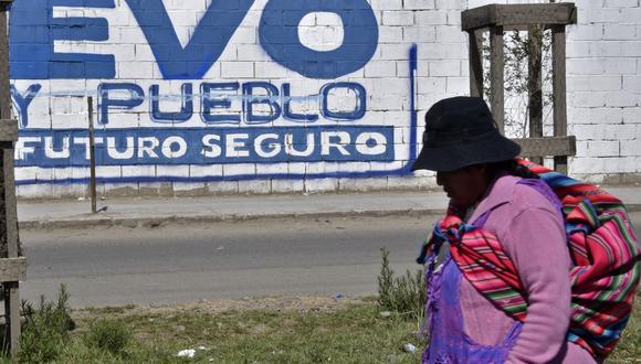 Una mujer indígena camina cerca de un muro con propaganda política que dice "Evo y el pueblo, futuro seguro", en referencia a la campaña de reelección del expresidente boliviano Evo Morales, en El Alto, Bolivia, el 20 de noviembre del 2019. (Foto de AIZAR RALDES / AFP).