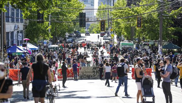 La gente camina alrededor de la recién creada "Zona Autónoma", en Seattle, Washington. El área rodea el edificio East Precinct. Los médicos voluntarios están disponibles para atender las necesidades médicas, junto con carpas con suministros médicos, comida gourmet donada de restaurantes locales, fruta, bocadillos, botellas de agua gratis para quien las necesite. (Jason Redmond / AFP)