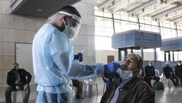 Un médico de Magen David Adom, el servicio de emergencia nacional de Israel, realiza pruebas de COVID-19 en palestinos que ingresan a Israel desde la Franja de Gaza en el cruce de Erez, en la frontera entre Israel y Gaza. (Foto: AP / Tsafrir Abayov)
