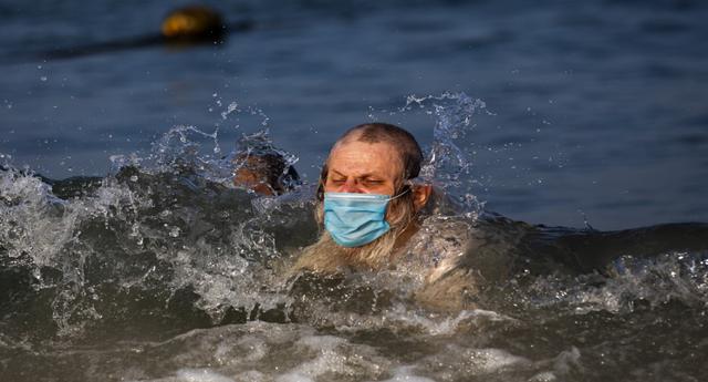 Un hombre judío ultraortodoxo, con una mascarilla, nada en el mar Mediterráneo, en una playa segregada para hombres tres días a la semana, en Tel Aviv (Israel). (Foto: Oded Balilty / AP)