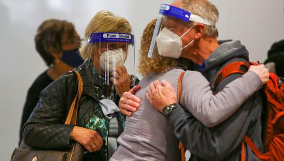 Viajeros con mascarillas y protectores faciales se despiden de sus familiares antes de tomar sus vuelos en el aeropuerto de Denver, Colorado. (Reuters)