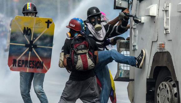 Manifestantes opositores arremeten contra un vehículo militar durante una protesta en Caracas. (AFP).