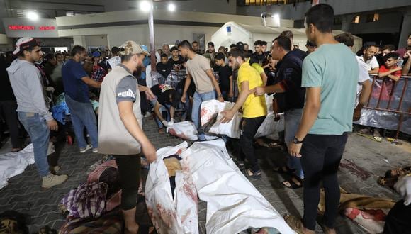 La gente se reúne alrededor de los cuerpos de los palestinos muertos después de que un ataque arrasara el hospital Ahli Arab en el centro de Gaza después de que fueron transportados al hospital Al-Shifa, el 17 de octubre de 2023. (Foto de Dawood NEMER / AFP)