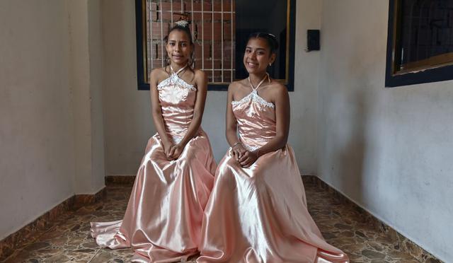 Sidneidy Uray, venezolana de 15 años, y su hermanastra Eikalin González posan para una foto con los mismos vestidos que usaron su madre y madrastra, y su hermana gemela para su cumpleaños número quince. (Foto de Federico Parra / AFP).