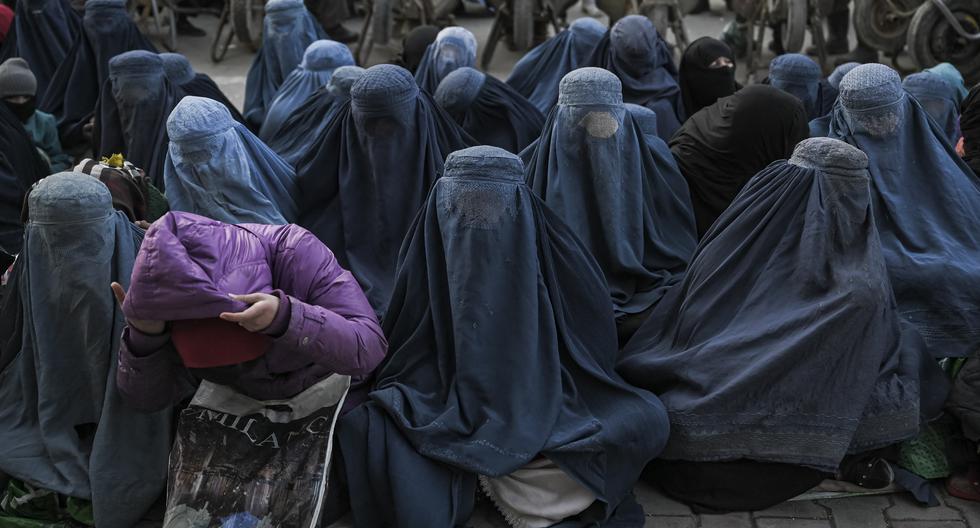 En esta foto de archivo tomada el 24 de enero de 2022, mujeres afganas vestidas con burka esperan pan gratis frente a una panadería en Kabul. (Foto de Mohd RASFAN / AFP).