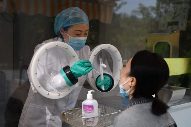 Una persona toma una muestra para analizar el coronavirus (COVID-19) de un miembro del personal de la compañía de biotecnología Coyote, que fabrica la máquina Flash 20. Foto registrada en Beijing, China. (AFP / GREG BAKER).