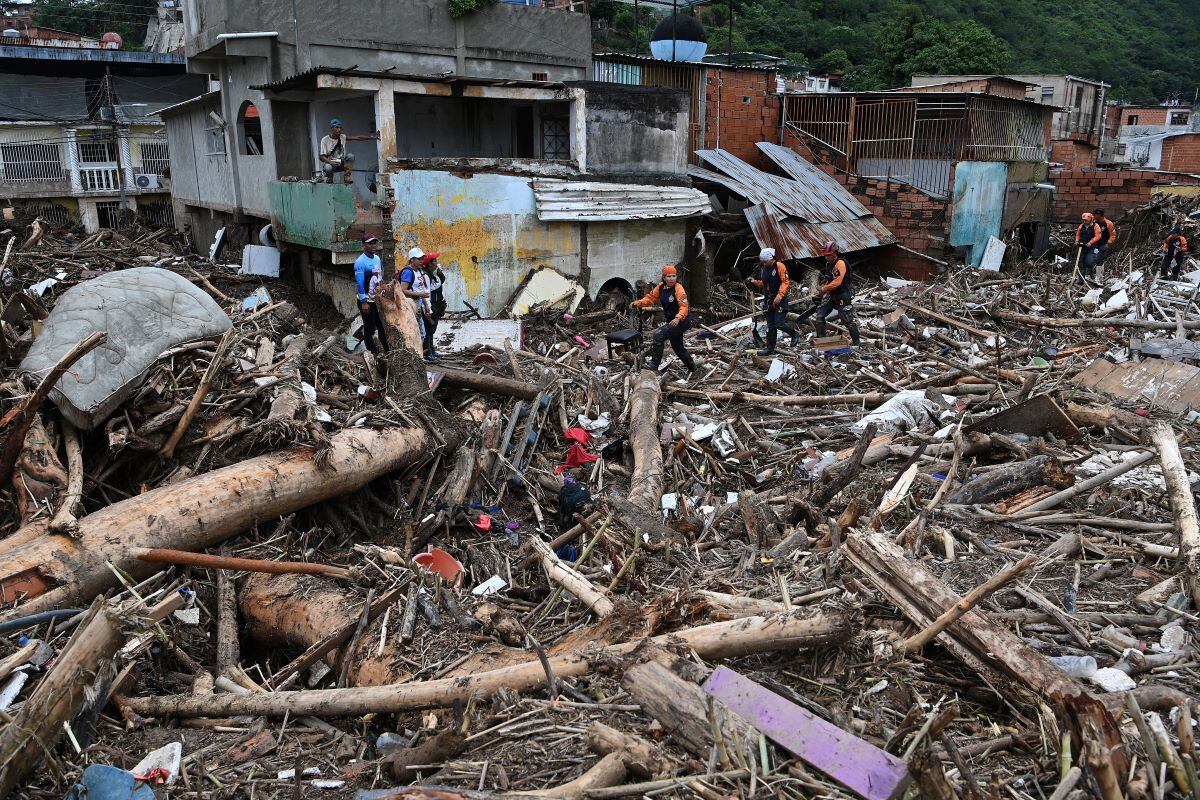 Rescue teams and family members search through the rubble of houses washed away by a rising stream in Las Tejerías, Aragua state, Venezuela.  (YURI CORTEZ / AFP).