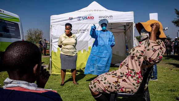 Un trabajador de la salud interactúa con los residentes de Diepsloot mientras esperan ser examinados en una estación temporal de prueba de coronavirus. (Foto: AFP / Emmanuel Croset).