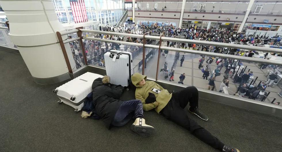 Un par de viajeros duerme mientras otros hacen cola abajo para pasar por el puesto de control de seguridad en el Aeropuerto Internacional de Denver en plena tormenta invernal en Estados Unidos. (Foto AP/David Zalubowski).