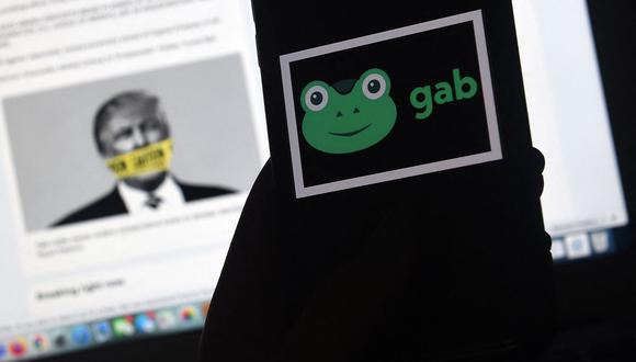 Esta imagen ilustrativa muestra el logotipo de la aplicación Gab en un teléfono inteligente con su sitio web y la foto de Donald Trump amordazado. (Foto de Olivier DOULIERY / AFP).