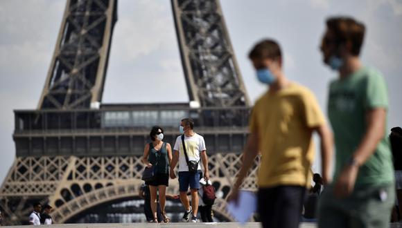 Personas con mascarillas caminan frente a la Torre Eiffel como parte de las medidas para contener la propagación del coronavirus en París (Francia). (EFE/EPA/Julien de Rosa).