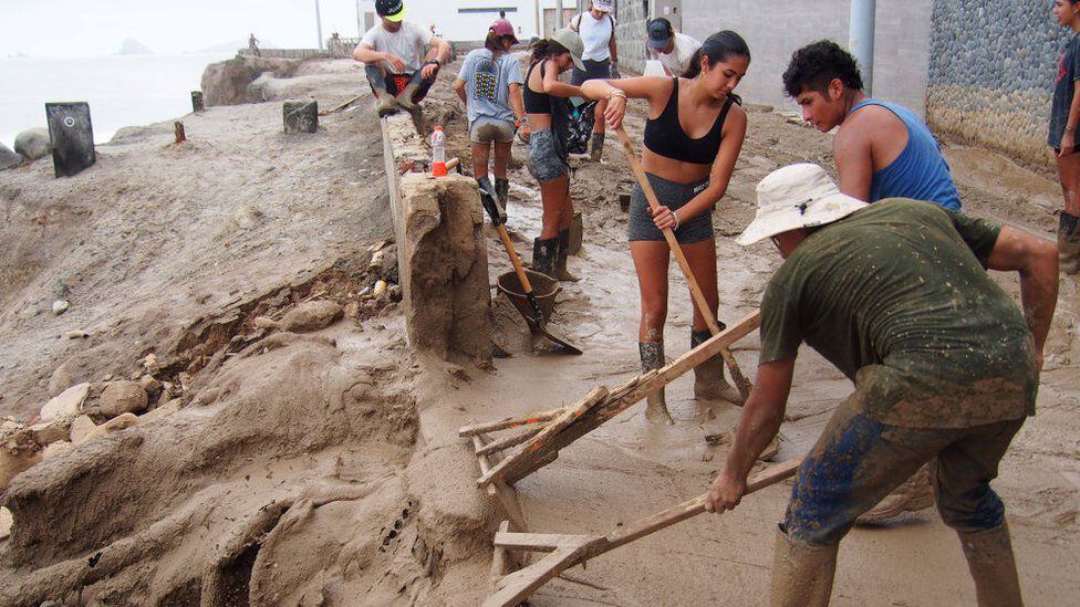 A group of people clear mud after an El Niño-related flooding off the coast of Peru.  (GETTY IMAGES).