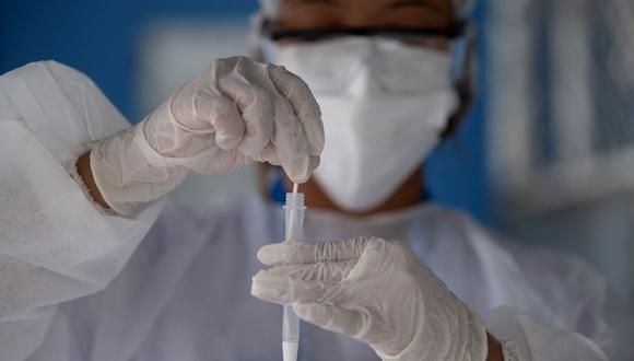 Una profesional de salud recolecta una prueba de para detectar el coronavirus en el Complexo do Alemao, ubicado enRío de Janeiro, Brasil , el 10 de diciembre de 2021. (MAURO PIMENTEL / AFP).