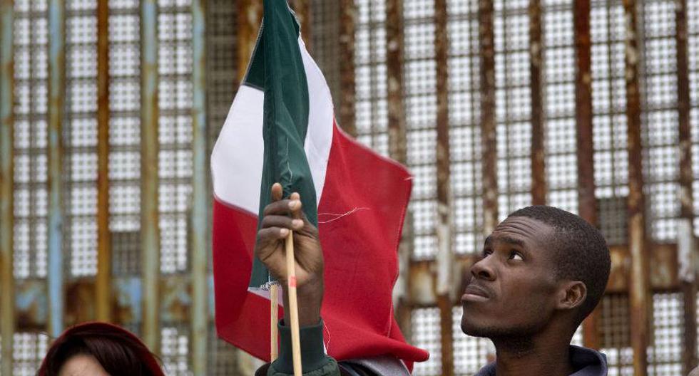 Una persona levanta una bandera mexicana junto a la cerca que marca el l&iacute;mite de la frontera de M&eacute;xico con EE.UU. (Foto: EFE)
