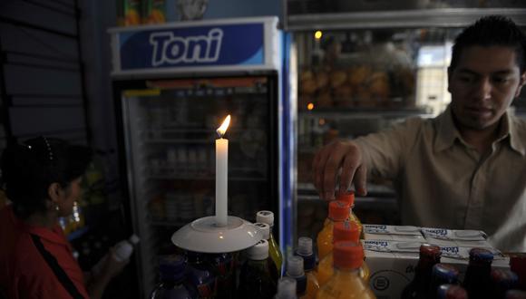 Un hombre trabaja en la penumbra tras un corte de luz debido a una crisis eléctrica el 10 de noviembre de 2009 en Quito. (Foto de RODRIGO BUENDIA / AFP)