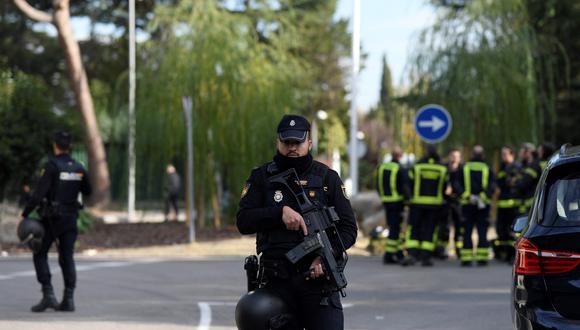 Un policía español se encuentra junto a los bomberos mientras aseguran el área después de la explosión de una carta bomba en la embajada de Ucrania en Madrid el 30 de noviembre de 2022. (Foto: OSCAR DEL POZO / AFP)