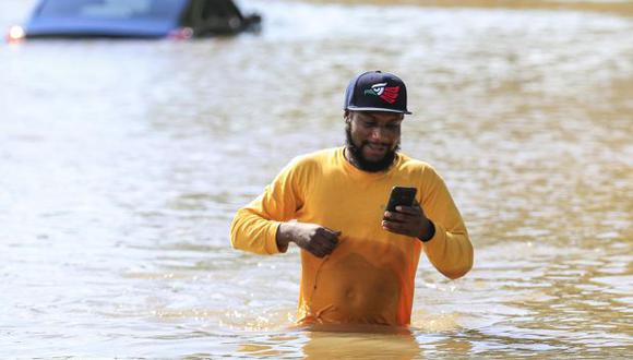 Un hombre camina por las aguas con su móvil tras las inundaciones de la crecida del río Buffalo Bayou debido al huracán Harvey en Houston, en el estado de Texas, Estados Unidos. (Foto: EFE)