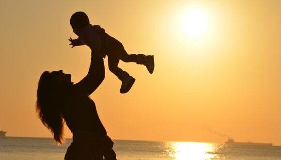 Mujer cargando a su bebé en la playa durante el ocaso. (Imagen: Pixabay / Pexels)