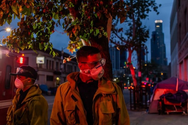 Los paramédicos de LAFD Station No9 esperan afuera de un hotel durante la pandemia del coronovirus en Skid Row, para brindar atención médica a un hombre sin hogar en el centro de Los Ángeles, California (Foto: Apu Gomes / AFP)